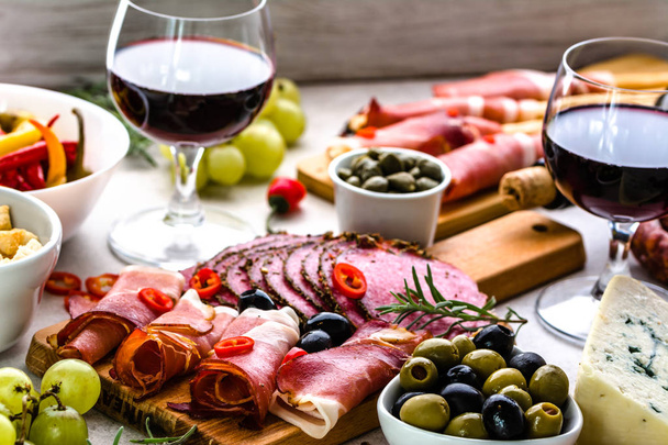 Selection of food, wine snack set on table, italian antipasti, prosciutto, salami, olives, cheese and other appetizer on platter - Foto, Bild