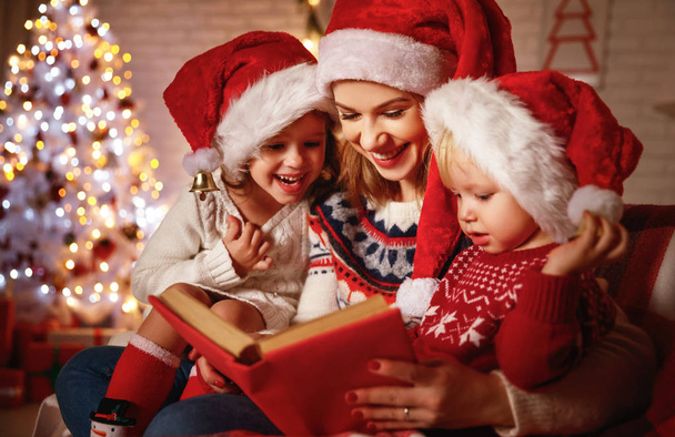 Familienmutter und Kinder lesen an Weihnachten in der Nähe der Feuerwache ein Buch - Foto, Bild