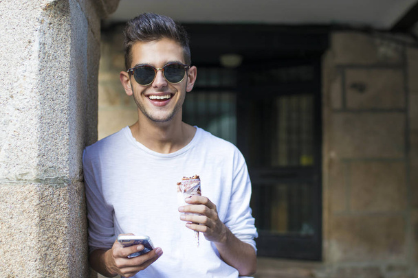 tizenéves fiatalember, mozgatható telefon és fagylalt a város utca - Fotó, kép