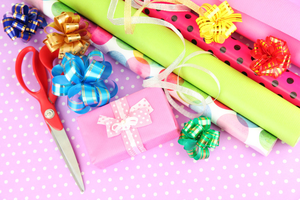 Rolls of Christmas wrapping paper with ribbons, bows on color background - Foto, afbeelding
