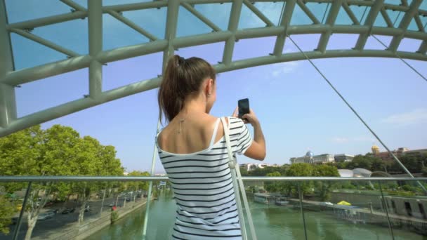Una giovane signora che scatta foto sul ponte sul fiume
. - Filmati, video