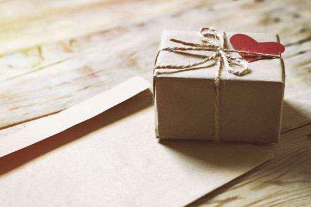 auf einem Holztisch einen Umschlag und eine Geschenkschachtel mit Herz - Foto, Bild