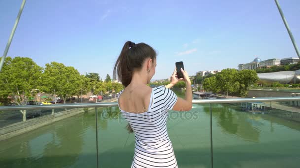 Una giovane signora che scatta foto sul ponte sul fiume
 - Filmati, video