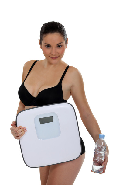 Woman in underwear carrying bathroom scales and water bottle - Zdjęcie, obraz