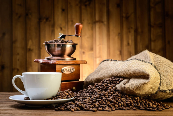 Stilleven met koffiebonen en oude koffiemolen op de houten achtergrond  - Foto, afbeelding