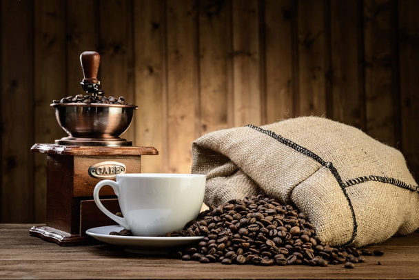 Stilleven met koffiebonen en oude koffiemolen op de houten achtergrond  - Foto, afbeelding