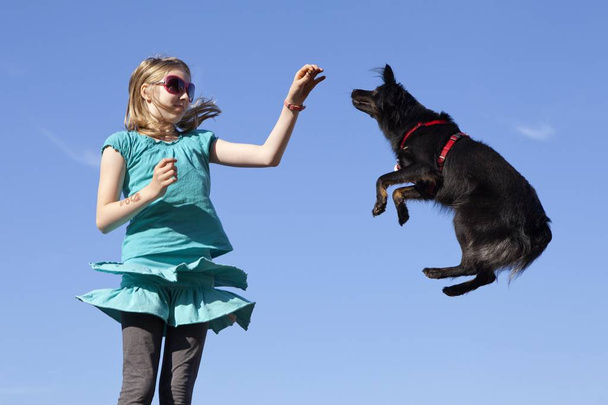 Girl making a dog jump - Фото, изображение