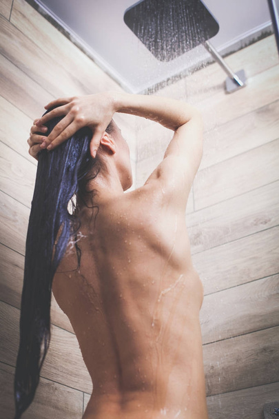 Young beautyful woman under shower in bathroom. - 写真・画像