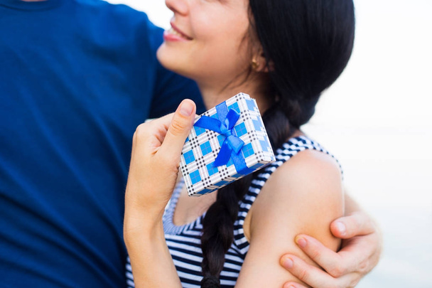 Young caucasian smiling brunette woman holding blue gift box - Foto, afbeelding