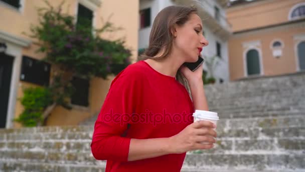 Busy woman talking on the smartphone while standing on the stairs outdoors - Filmagem, Vídeo