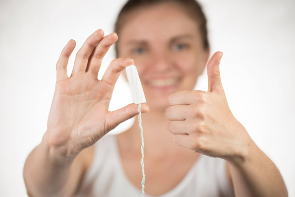 A young girl is holding a hygienic tampon showing a thumbs up on - Фото, зображення