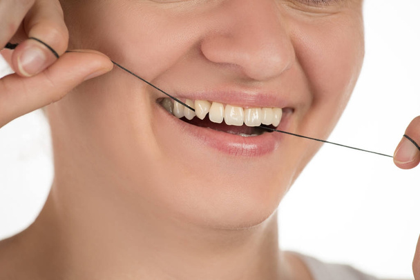 Hygiene der Mundhöhle. junges Mädchen putzt Zähne mit Zahnseide,  - Foto, Bild