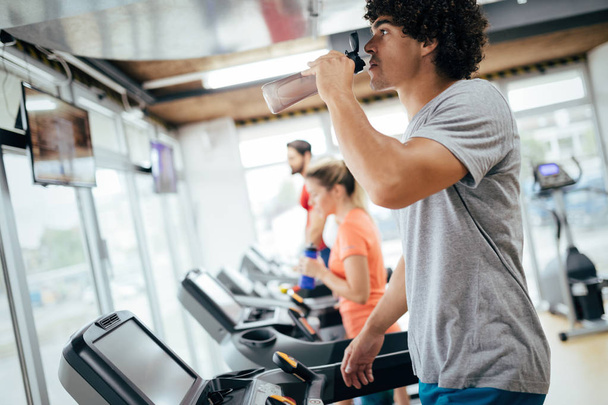 Young handsome man doing cardio training on treadmill in gym - Valokuva, kuva