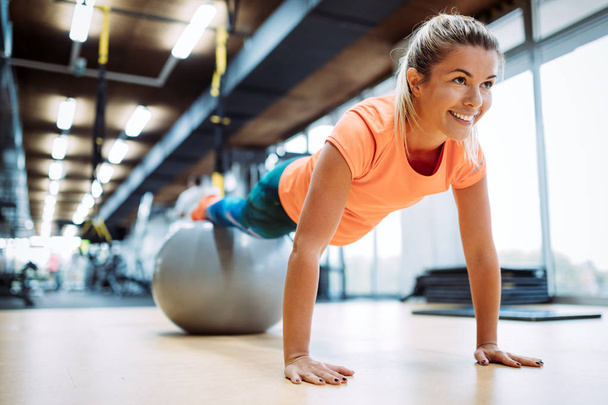 Young attractive woman doing push ups using ball in gym - Foto, immagini