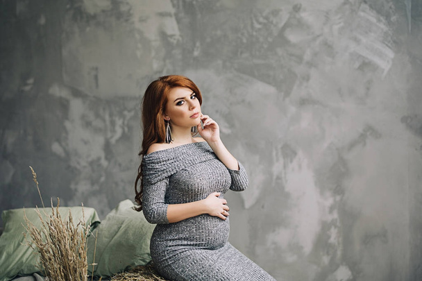 Mulher grávida bonita com longos cabelos vermelhos em um vestido, beleza da gravidez, esperando por uma criança, futuros pais, tornando-se uma mãe, nova vida
 - Foto, Imagem