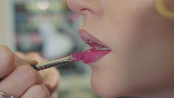 Young makeup artist applying lipstick on models lips. - Imágenes, Vídeo