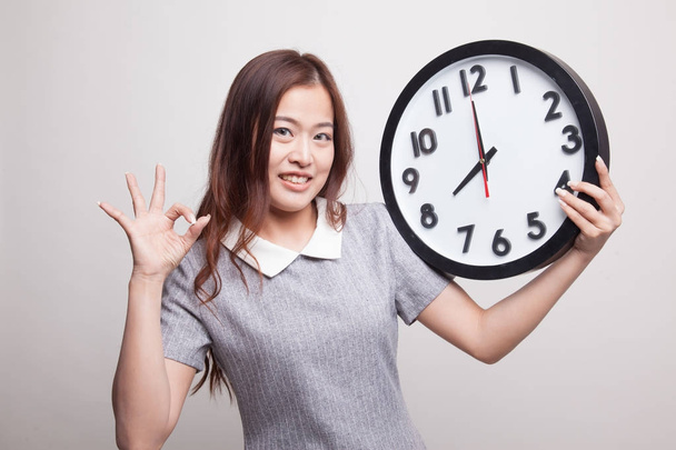 Young Asian woman show OK with a clock. - Foto, Imagen