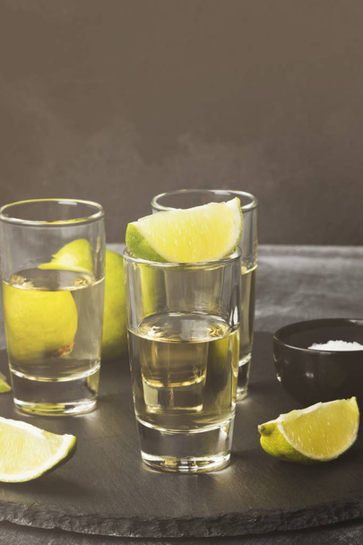 Tequila with lime and salt on a dark background. Toned - Фото, изображение