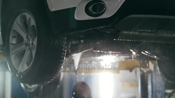 Washing luxury SUV under bottom in the suds by water hoses - under bottom, close up - Footage, Video