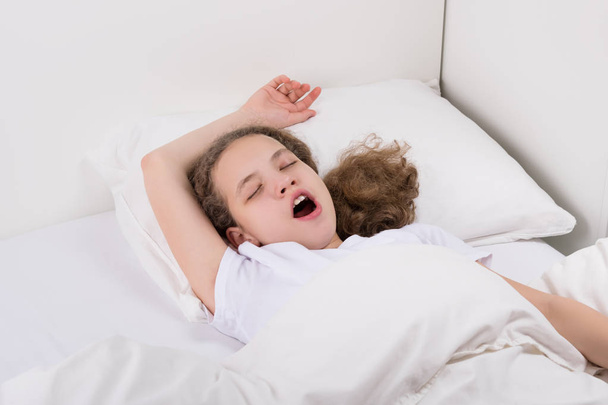 Mädchen im Bett zieht ihre Arme, um aufzuwachen - Foto, Bild