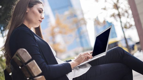 Woman using laptop computer in outdoors - Photo, Image