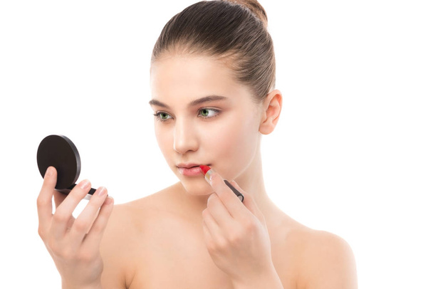 Young brunette woman with perfect clean face applying lipstick using mirror. Isolated on a white. - Φωτογραφία, εικόνα