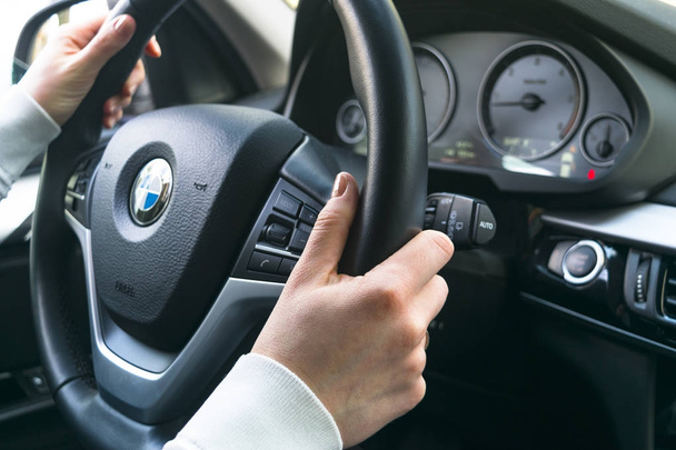 Woman's hands on a steering wheel driving BMW X5 F15. Hands holding steering wheel. Modern Car interior details. - Foto, afbeelding