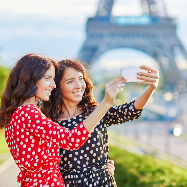 Twin sisters taking selfie near the Eiffel tower in Paris - Foto, Imagen