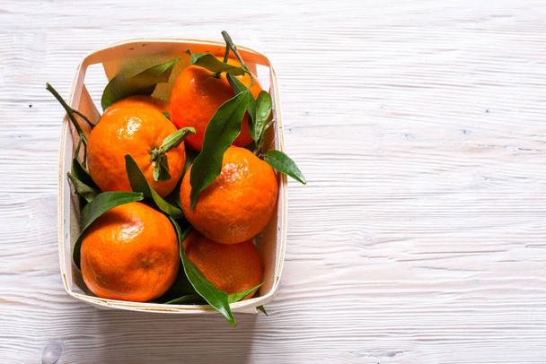 Fresh Mandarin with green leaves on wooden table - Фото, изображение