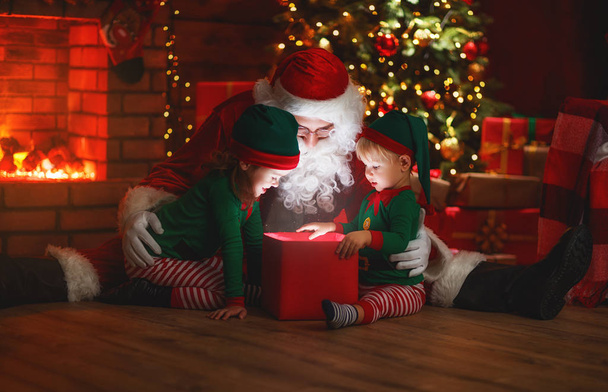 Weihnachtsmann und kleine Wichtel mit magischem Weihnachtsgeschenk - Foto, Bild