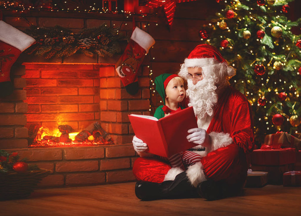 サンタ クロースがクリスマス ツリーに小さなエルフに本を読みます - 写真・画像