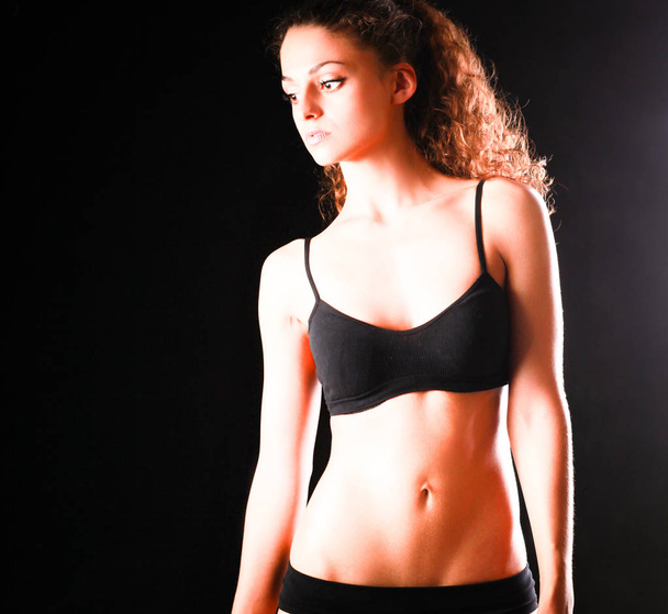 Portret van jonge mooie fitness vrouw, geïsoleerd op zwarte achtergrond - Foto, afbeelding