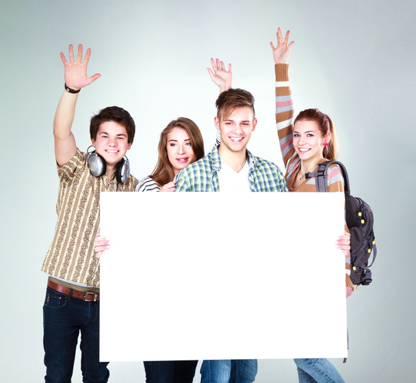 Grupo de jóvenes amigos sosteniendo un tablero en blanco, aislados sobre fondo blanco - Foto, Imagen
