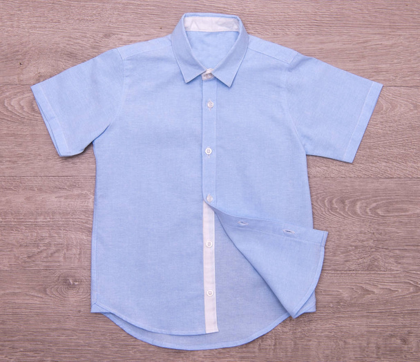 голубая рубашка для мальчиков на деревянном фоне
 - Фото, изображение