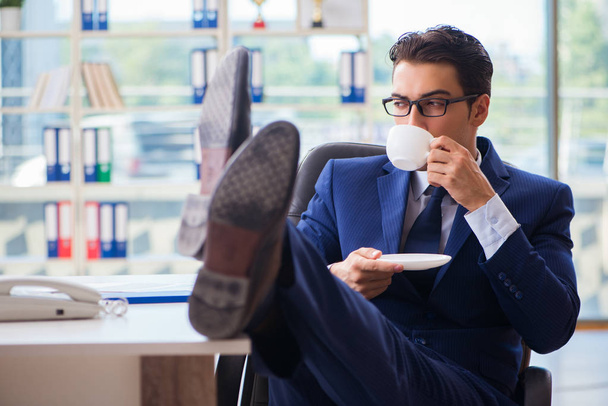 Businessman drinking coffee in the office during break - Foto, afbeelding