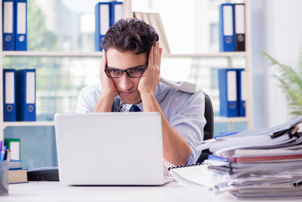 Молодой бизнесмен под давлением в офисе для выполнения задач - Фото, изображение