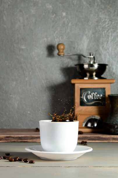 Taza de café con chapoteo sobre fondo de madera con frijoles
. - Foto, Imagen