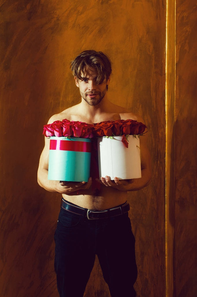 bearded muscular man with sexy body holds red rose box - Foto, Bild