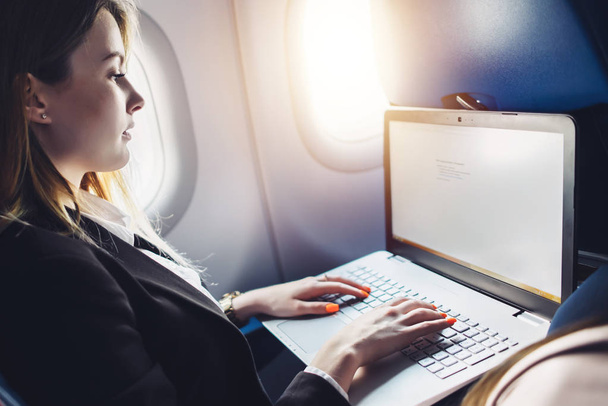 Nuori nainen opiskelija oppimisen verkossa kautta netbook istuessaan lentokoneessa mökki
 - Valokuva, kuva