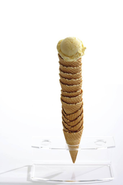 Stack of ice-cream cones placed in a stand and topped with a scoop of ice-cream - Fotó, kép