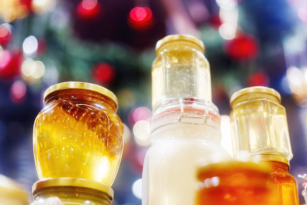 Holiday fair. Jars of honey glowing in garlands of lighting bulb - Foto, afbeelding