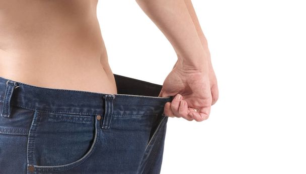 Bir kadın bir kilo kaybı eski büyük pantolon giyerek gösterir. Kilo kaybı kavramı - Fotoğraf, Görsel