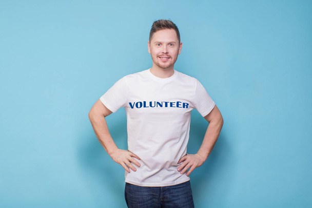 Glimlachende man in wit T-shirt op blauwe achtergrond - Foto, afbeelding