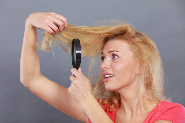 Woman looking at hair through magnifying glass - Zdjęcie, obraz