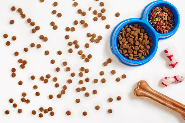 Dry pet food in bowl and bone on white background top view - 写真・画像