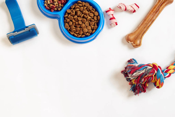 Pflegeartikel für Hunde, isoliert auf weißem Hintergrund. Trockenfutter in Schalen, Spielzeug und Knochen. Ansicht von oben - Foto, Bild