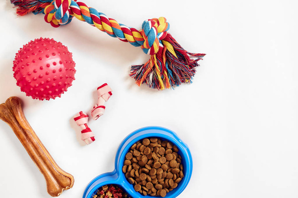 droog voedsel voor huisdieren in kom en speelgoed voor honden op witte achtergrond bovenaanzicht - Foto, afbeelding