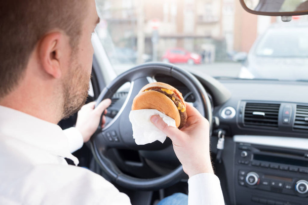 Człowiek, jedzenia fast foodów i jazdy w pozycji siedzącej w samochodzie - Zdjęcie, obraz