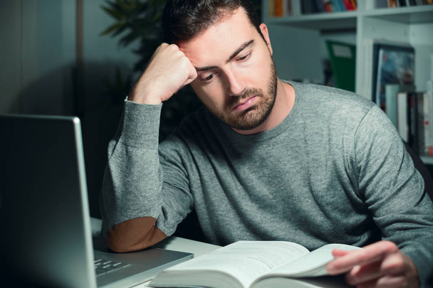 Estudiante masculino estresado estudiando hasta tarde en la noche
 - Foto, imagen