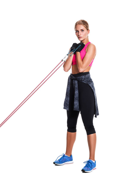 Сильная женщина использует бандаж сопротивления в своих упражнениях. Молодая женщина занимается фитнесом на белом фоне
. - Фото, изображение